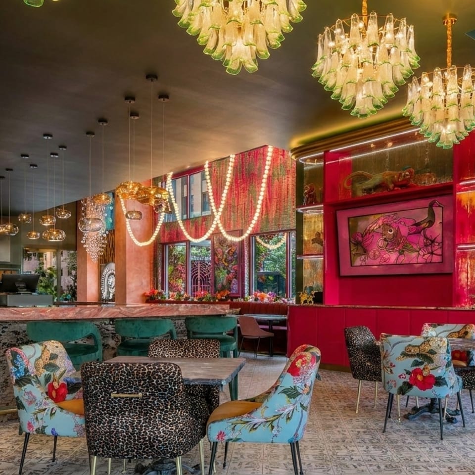 Vibrantly decorated restaurant interior with ornate chandeliers, patterned chairs, and a pink and green color scheme.